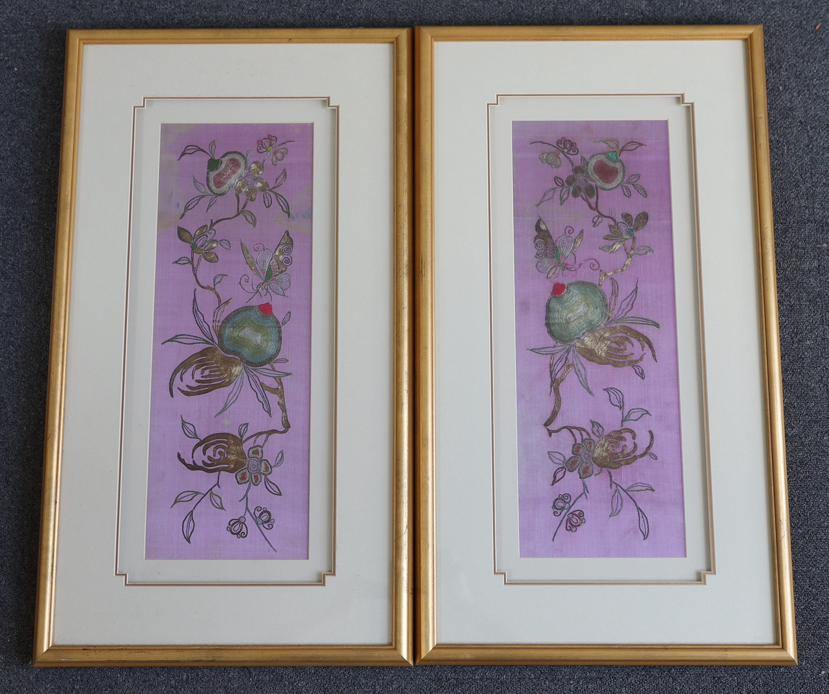 A pair of late 19th century Chinese purple silk, multi-coloured metallic thread embroideries, decorated with fruits and butterflies, mounted and framed, 8cm wide, 48cm high